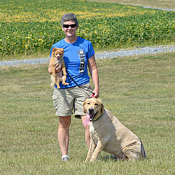 Sandy holds her Pomeranian puppy, Cricket, with Cooper, her Golden Retriever sitting in front of her